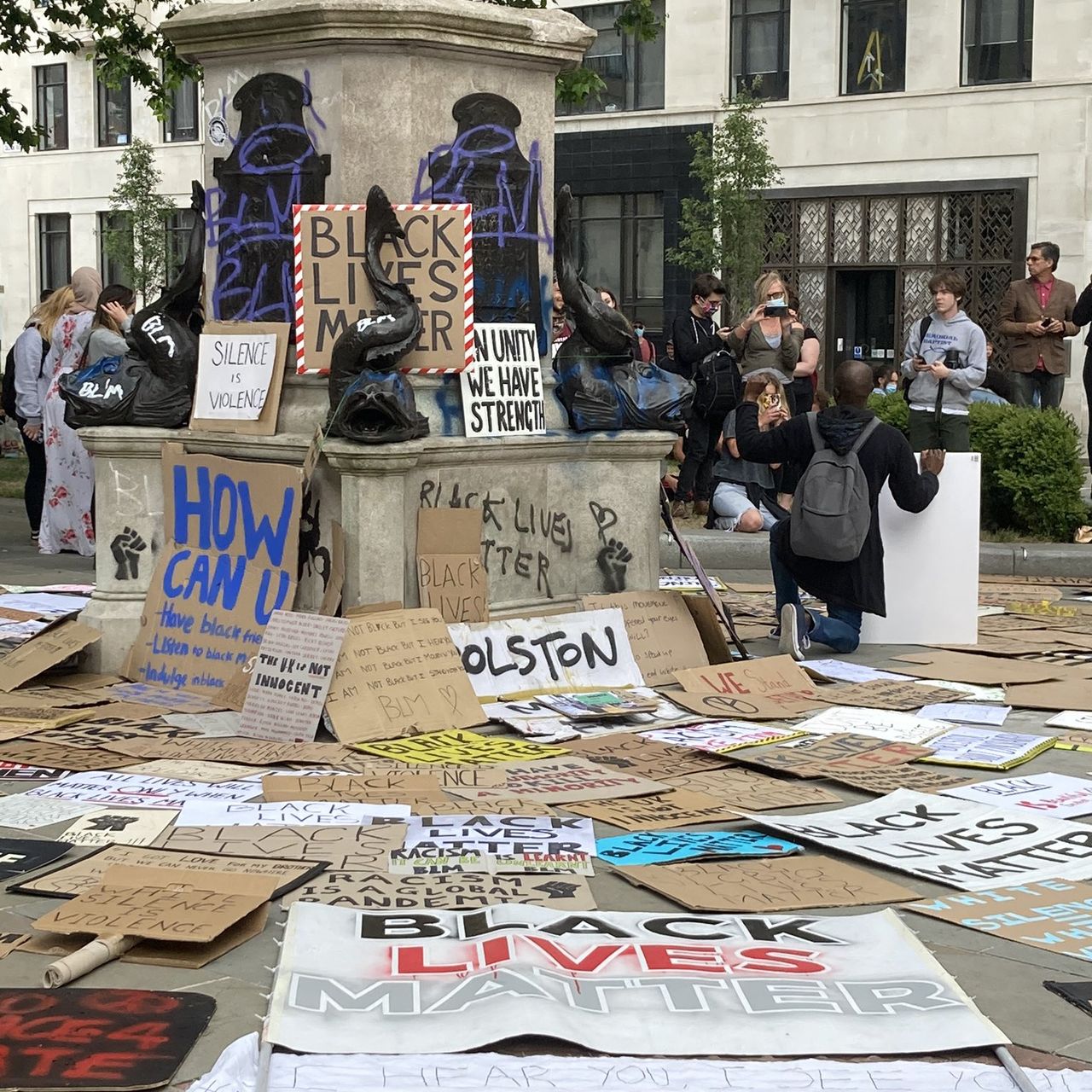 The empty pedestal of a Bristol slaver, after the statue was toppled, defaced, and pushed into Bristol Harbour, showing placards and graffiti.